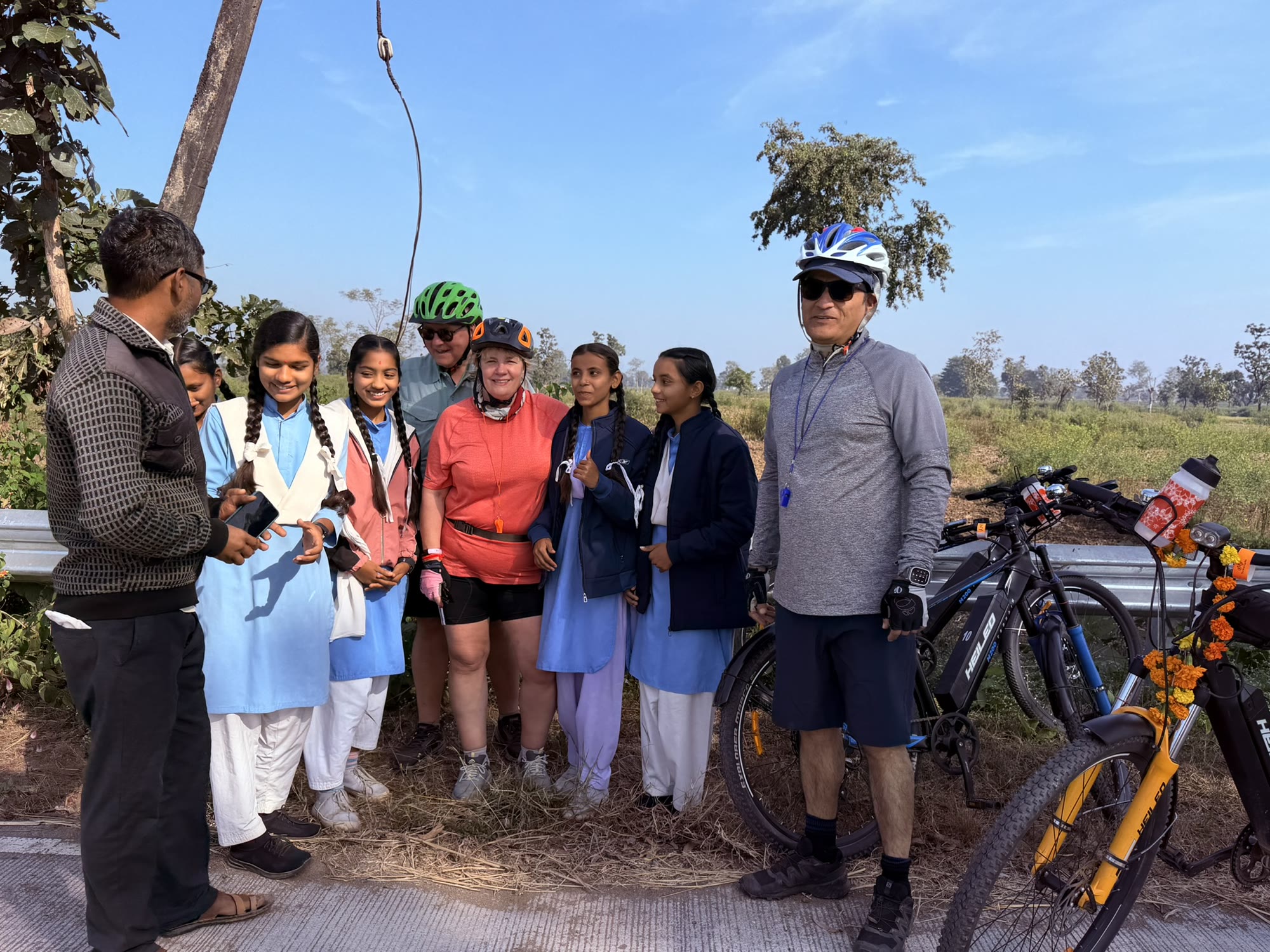 Guests on a cycling safari stopping to talk with schoolgirls on a village road beside the forest in central India