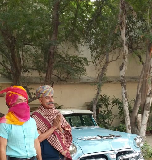 Two hosts in Rajasthani turbans and scarves beside a classic car on the vintage car ride in Jaipur