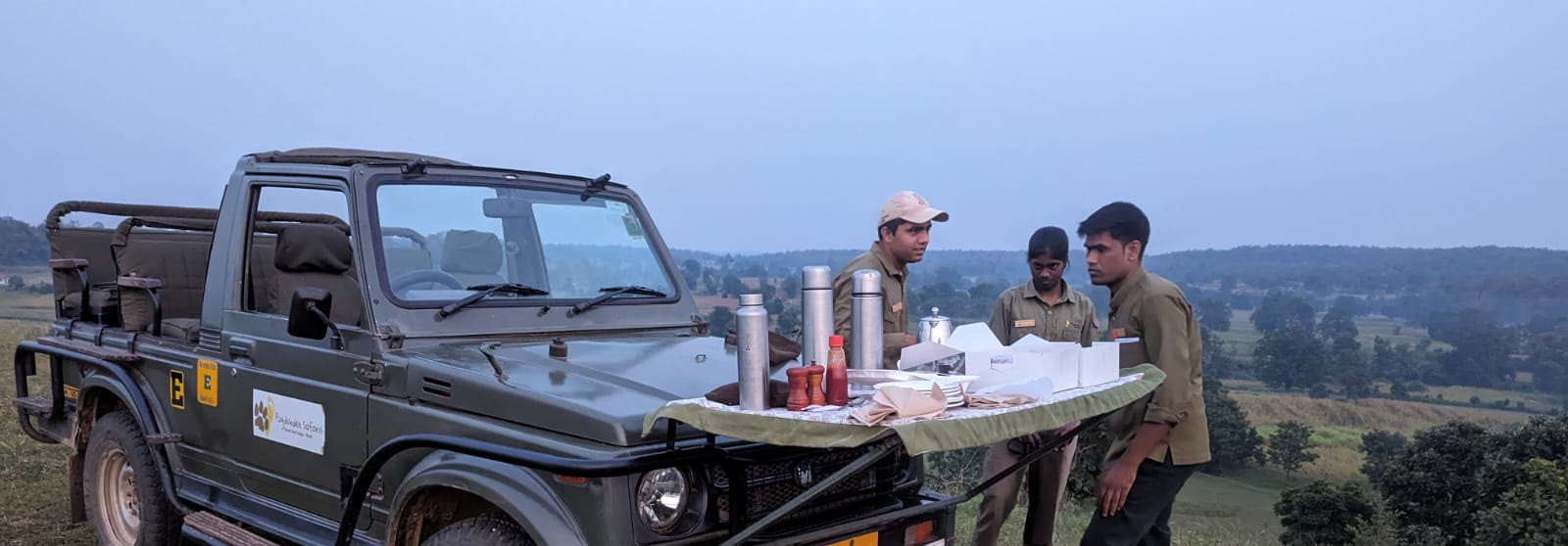 Naturalists setting out breakfast on a safari jeep above the Pench valley at dawn
