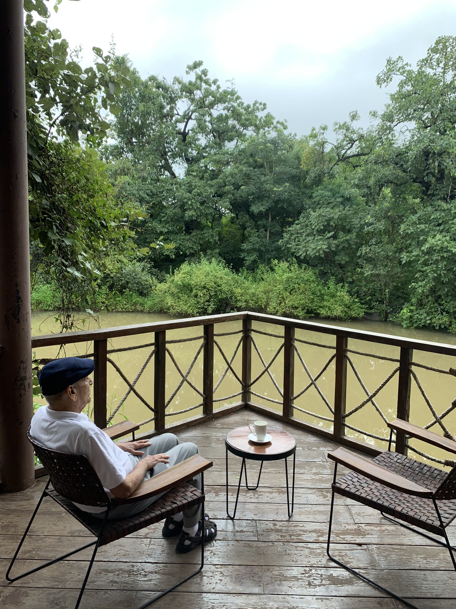 A guest relaxing on the deck of a cottage at Pench Tree Lodge, looking out over the forest