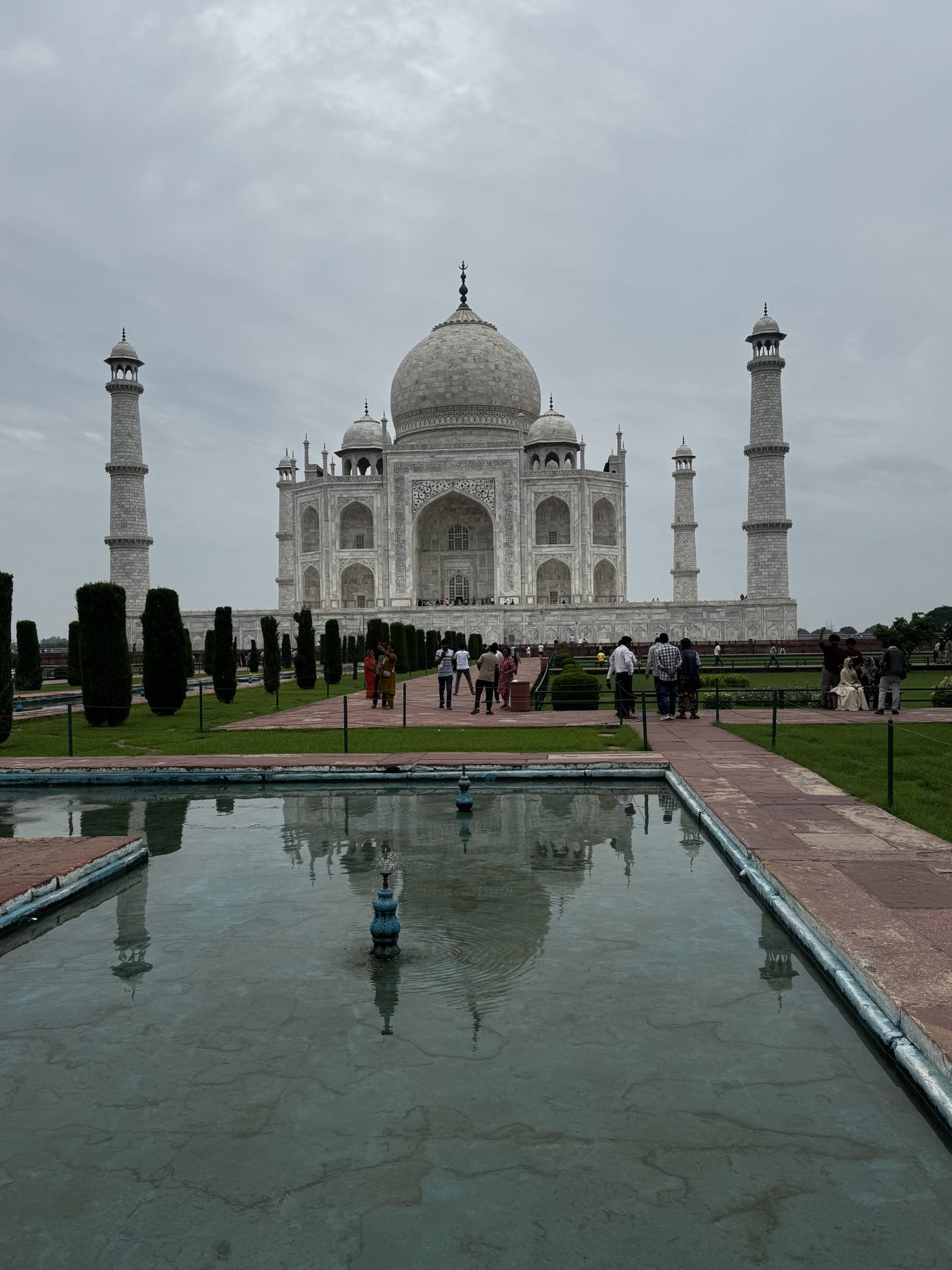 The Taj Mahal and its four minarets reflected in a garden pool beneath monsoon clouds, Agra