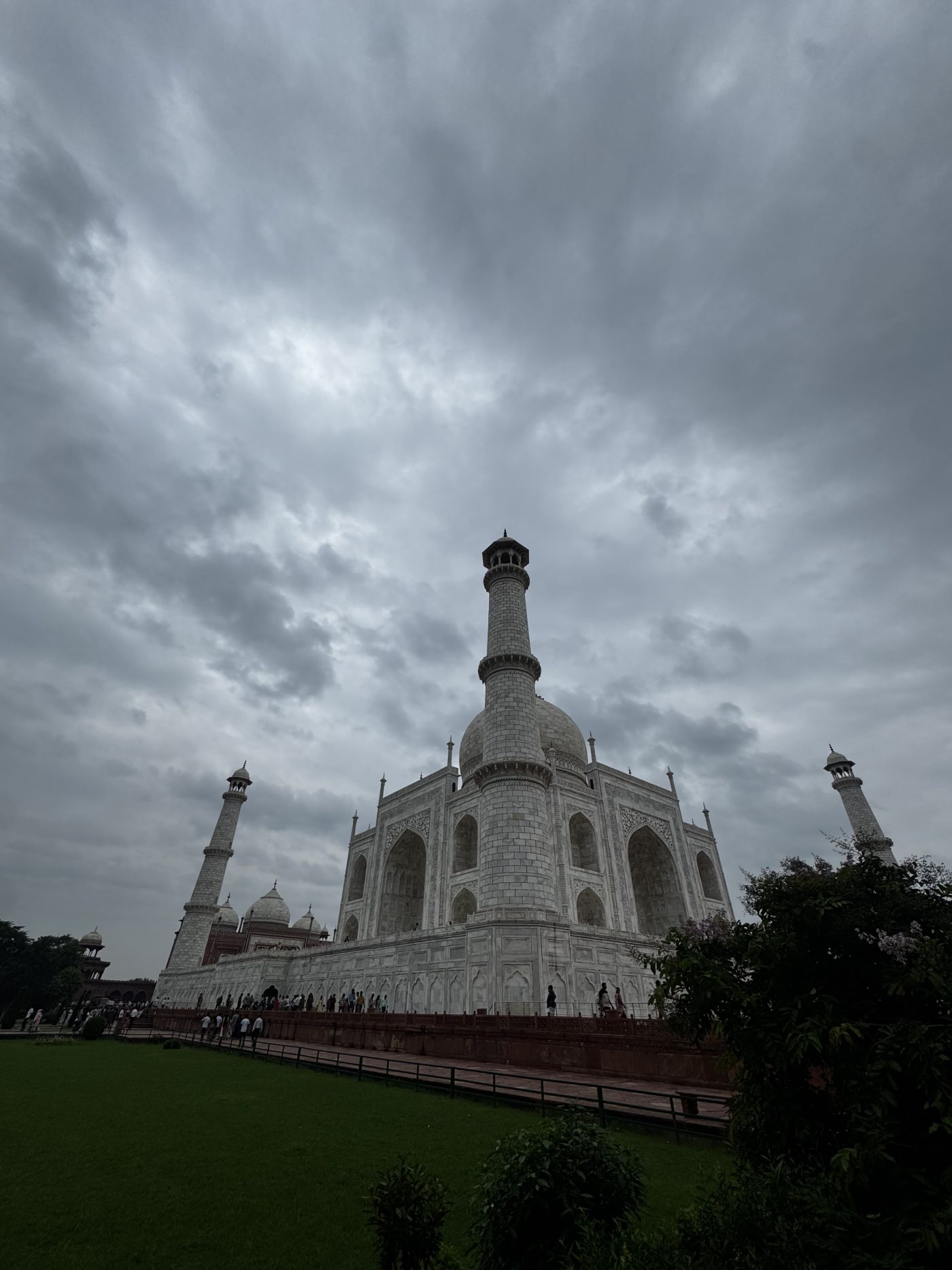 The Taj Mahal seen from a corner of its gardens, rising beneath a sky of grey monsoon cloud, Agra