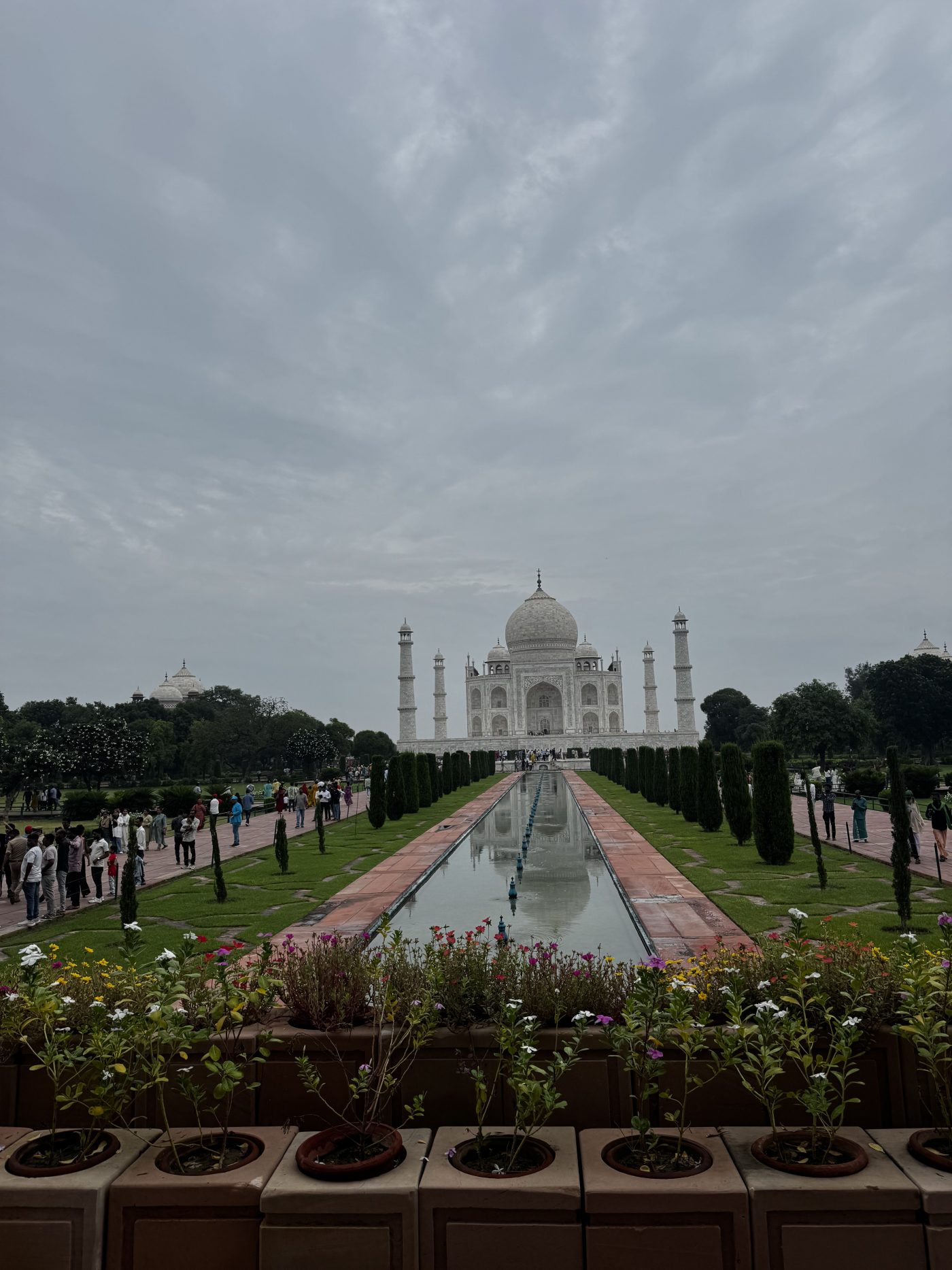 The Taj Mahal at the end of its long reflecting pool, seen across flower beds in the Mughal gardens, Agra
