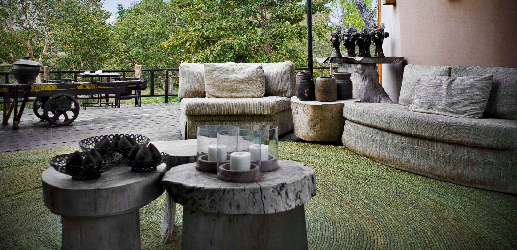 A lounge deck with sofas and carved wooden stools at Banjaar Tola