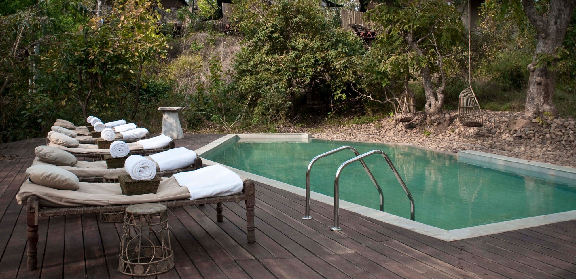 Sun loungers beside a pool on a wooden deck at Banjaar Tola