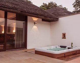 A private plunge pool on a terrace beside a thatched cottage at Khem Vilas