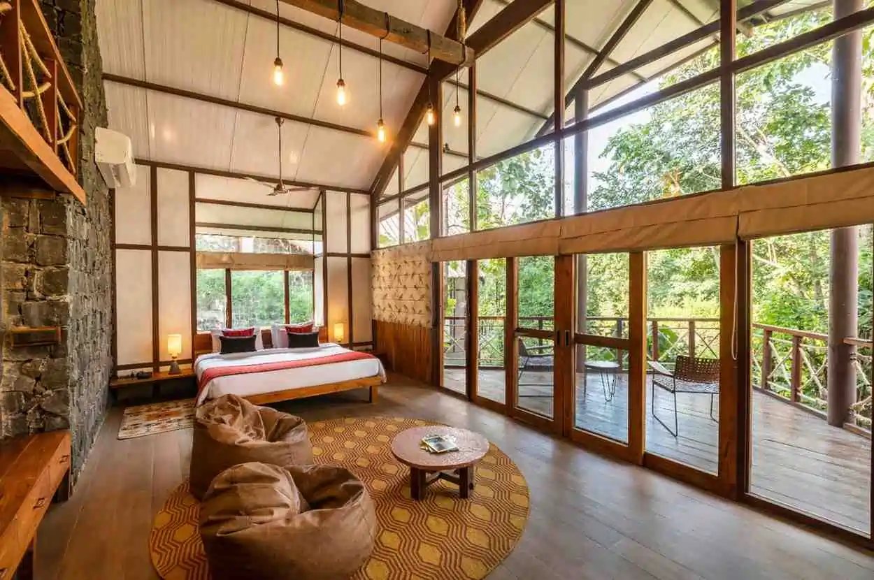 A cottage room at Pench Tree Lodge with a high timber roof and glass walls