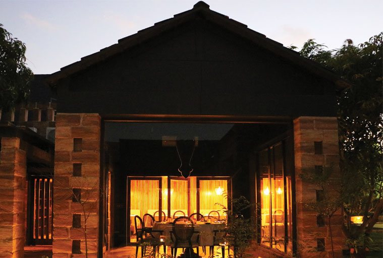 The glass-walled dining pavilion at Postcard Gir, lit up at dusk