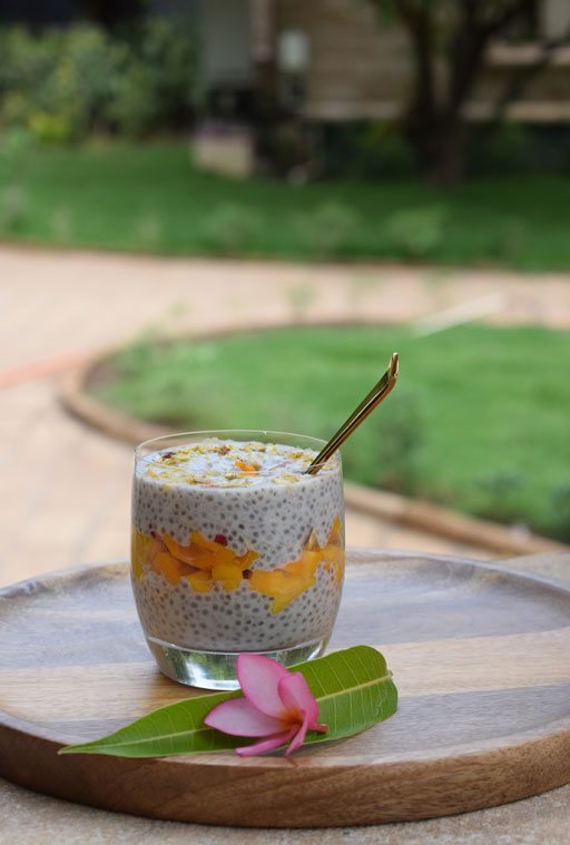 A glass of chia pudding with mango on the lawn at Postcard Gir