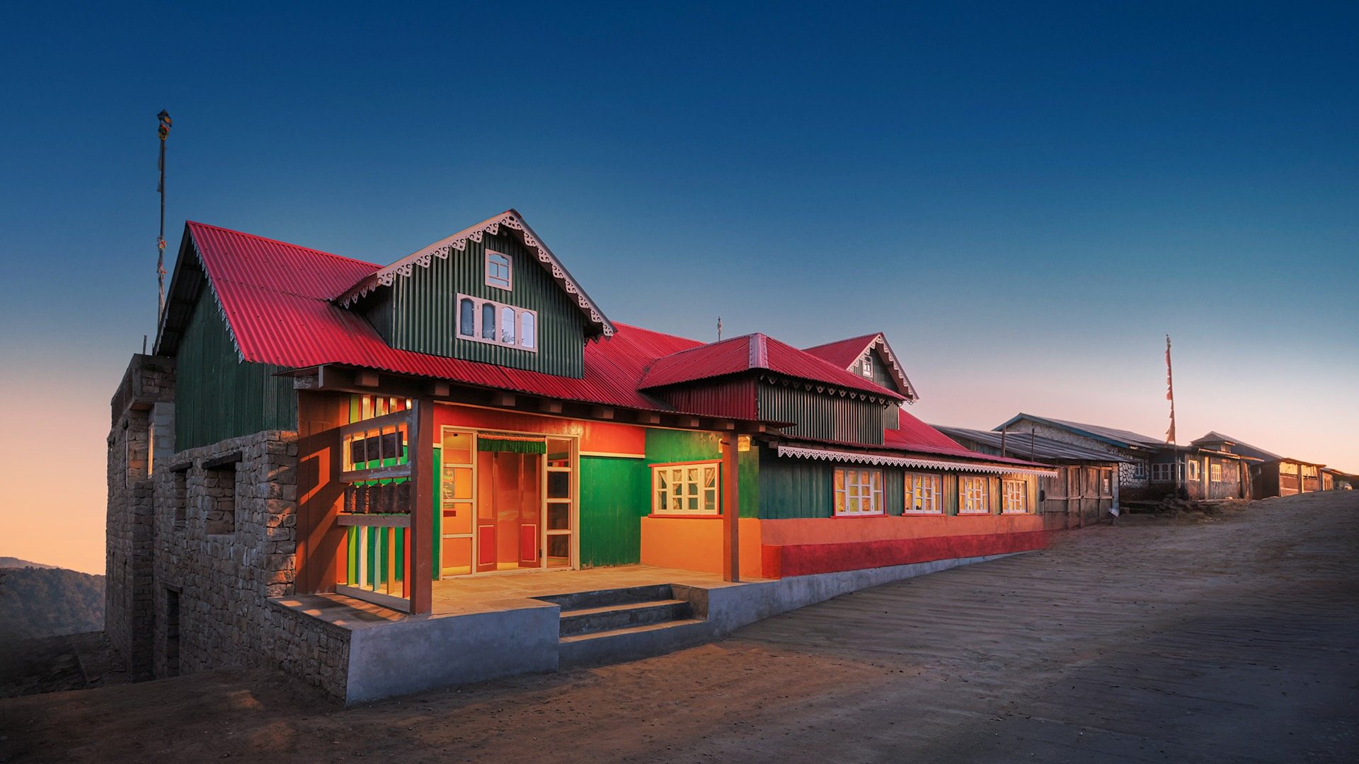 Red Panda Outpost at dusk, a painted timber lodge with a red roof