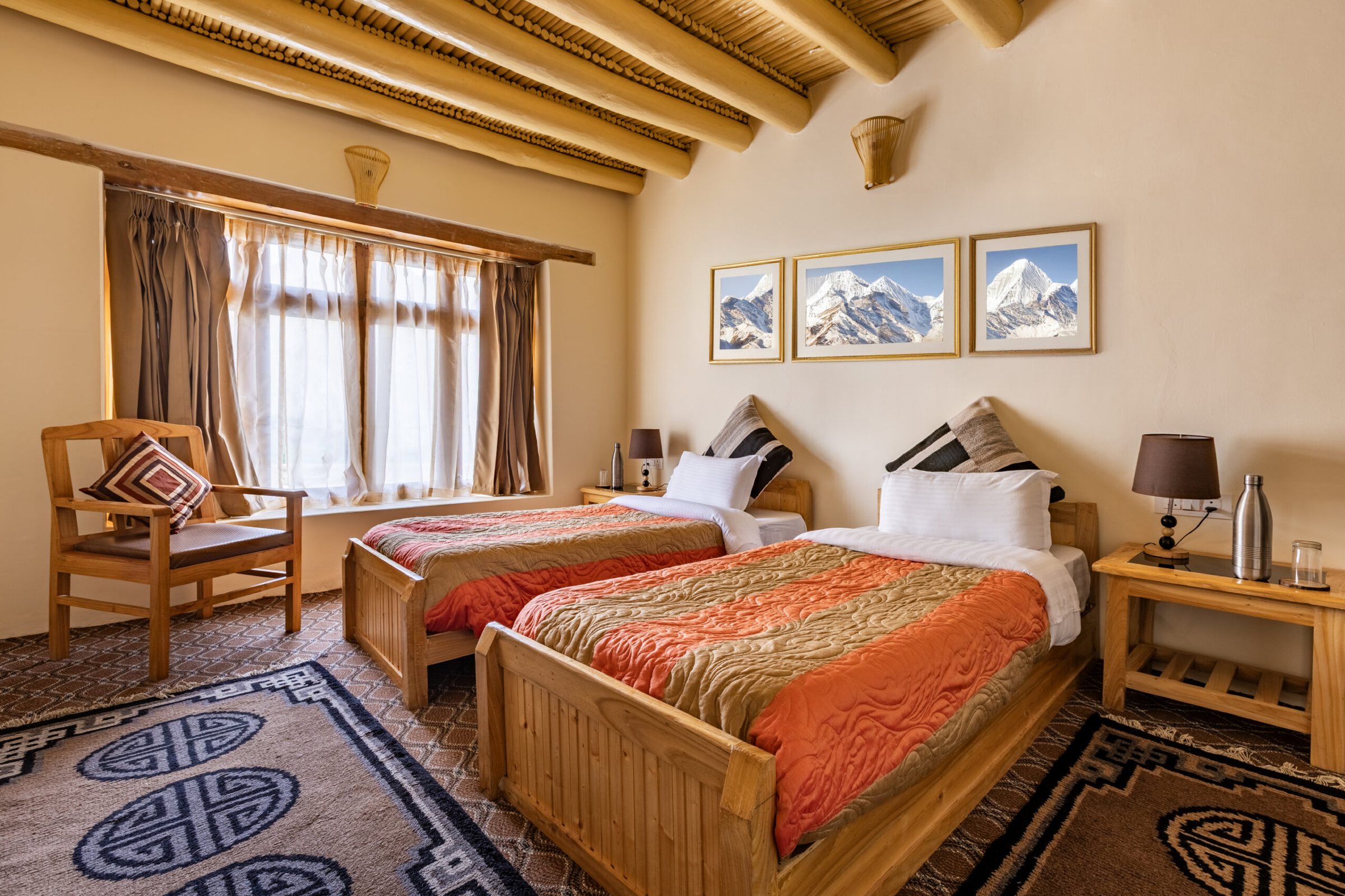 A twin bedroom at Snow Leopard Lodge with Ladakhi rugs and mountain prints
