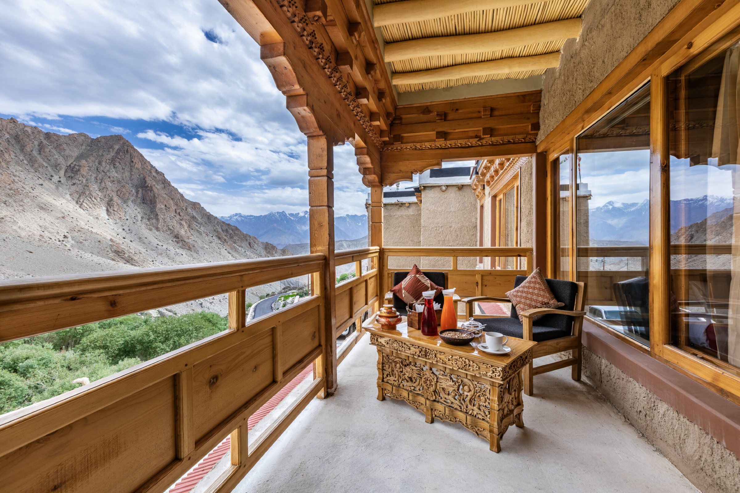 A veranda at Snow Leopard Lodge with carved wooden furniture and mountain views