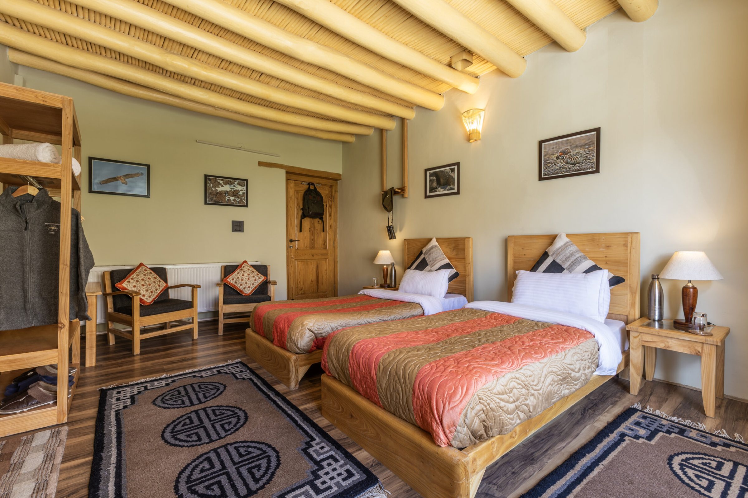 A twin room at Snow Leopard Lodge with a wardrobe and Ladakhi rugs