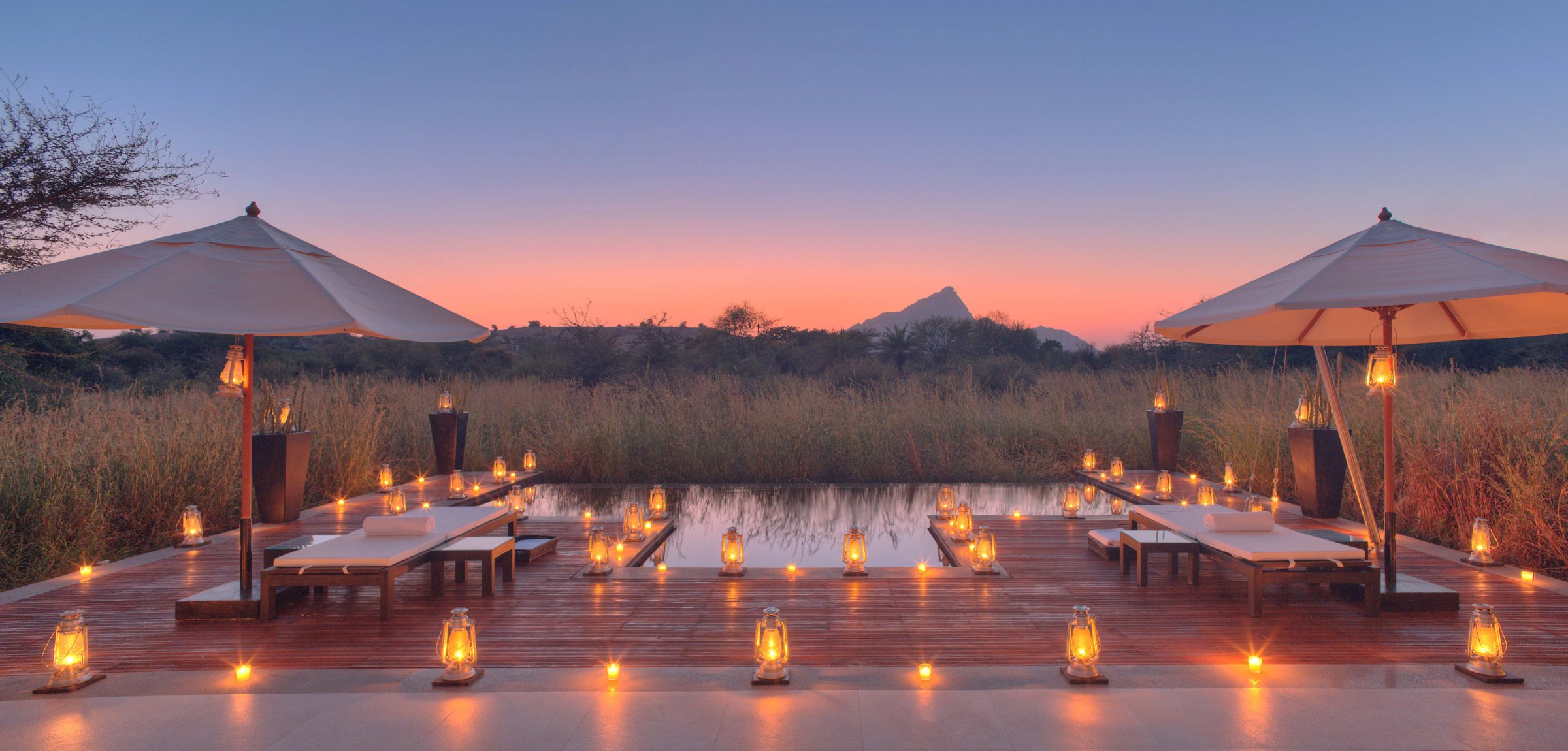 A lantern-lit deck with parasols at Sujan Jawai at sunset