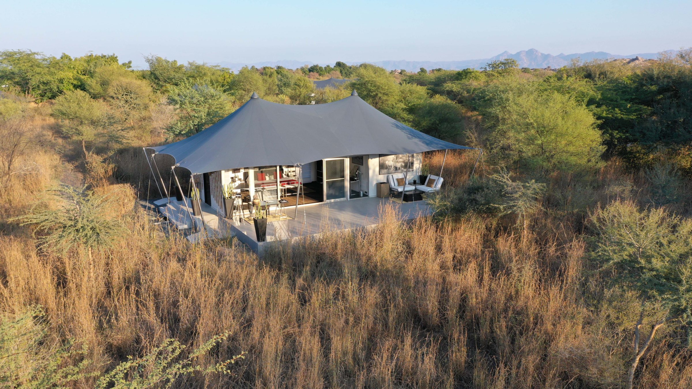 A tent at Sujan Jawai among scrub, with granite hills beyond