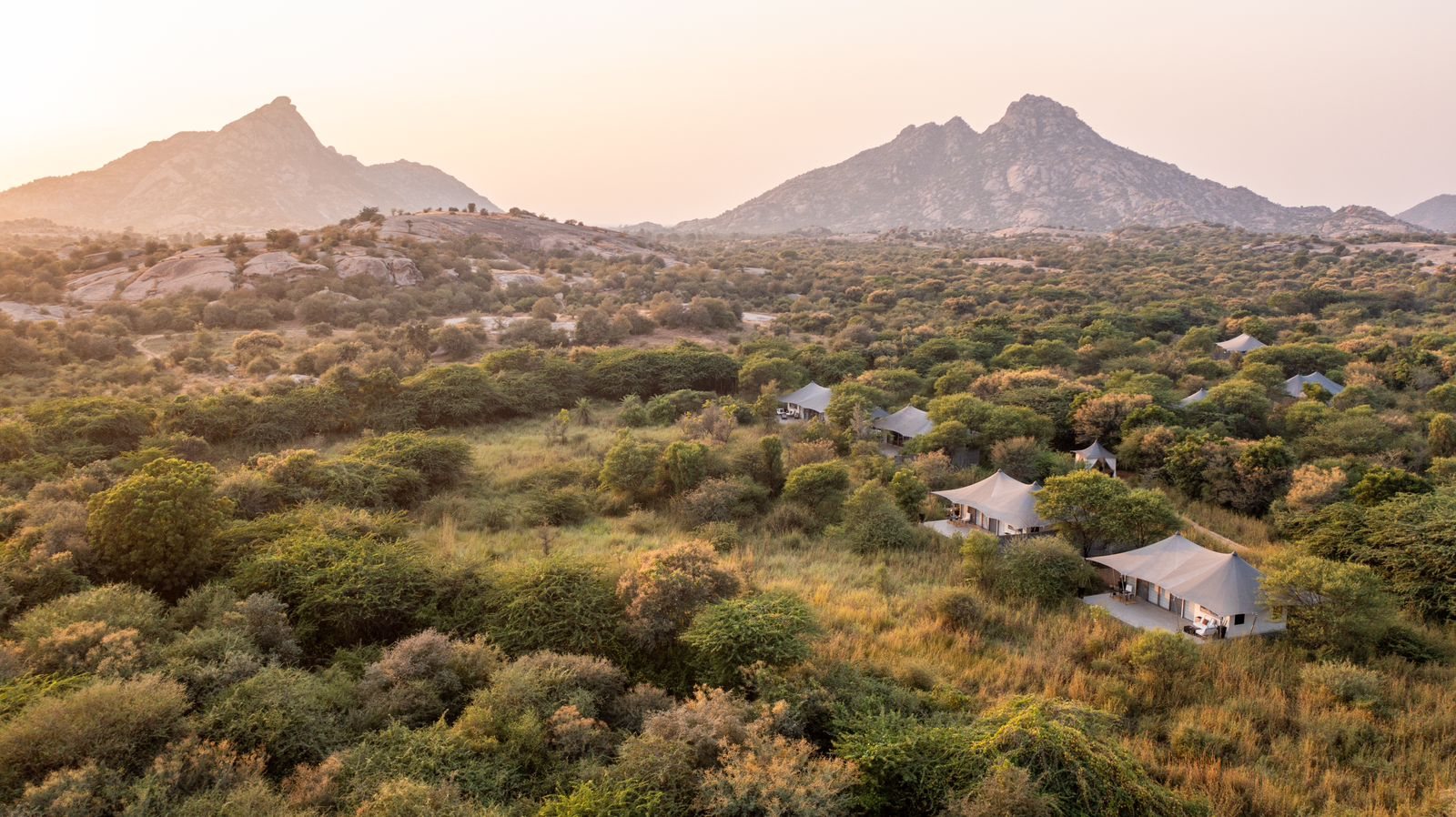 Granite peaks rising above the forest and tents of Sujan Jawai