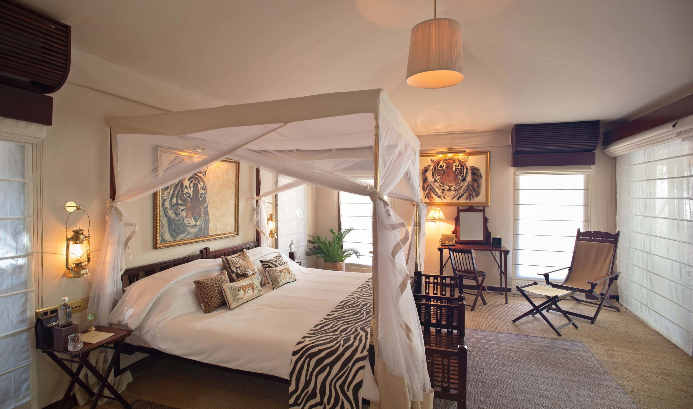 A four-poster bed with a mosquito net in a tent at Sujan Jawai