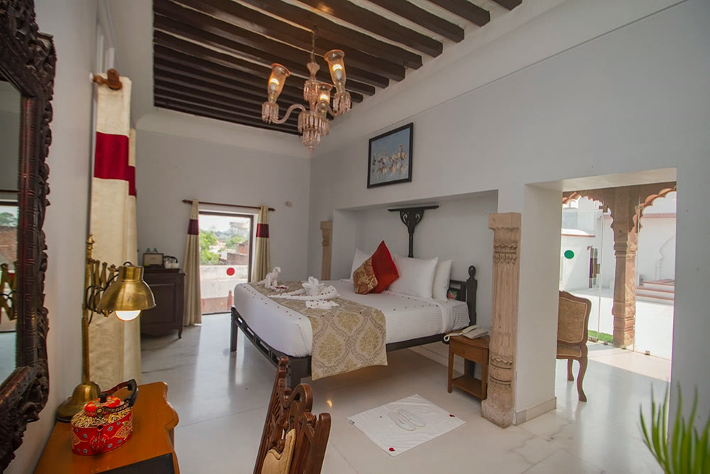 Room at Amritara Chandra Mahal Haveli, with a carved stone pillar and a chandelier