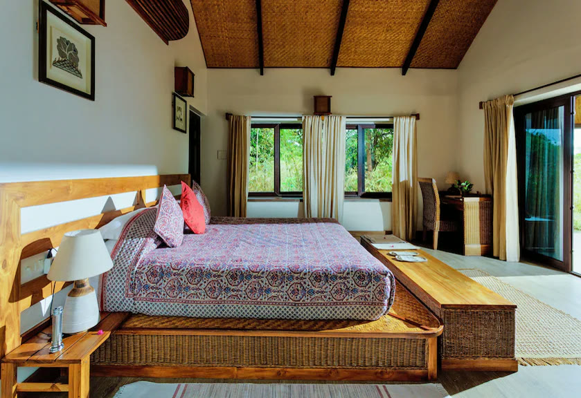 Room at Bagh Villas, with a cane bed, a block-printed bedspread and windows onto the forest