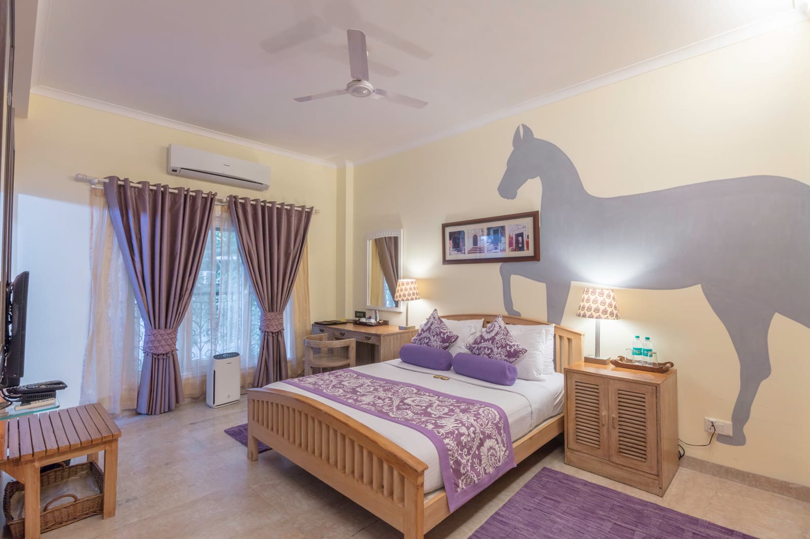 Bedroom at Colonel's Retreat, Delhi, with lilac linen and a horse painted on the wall