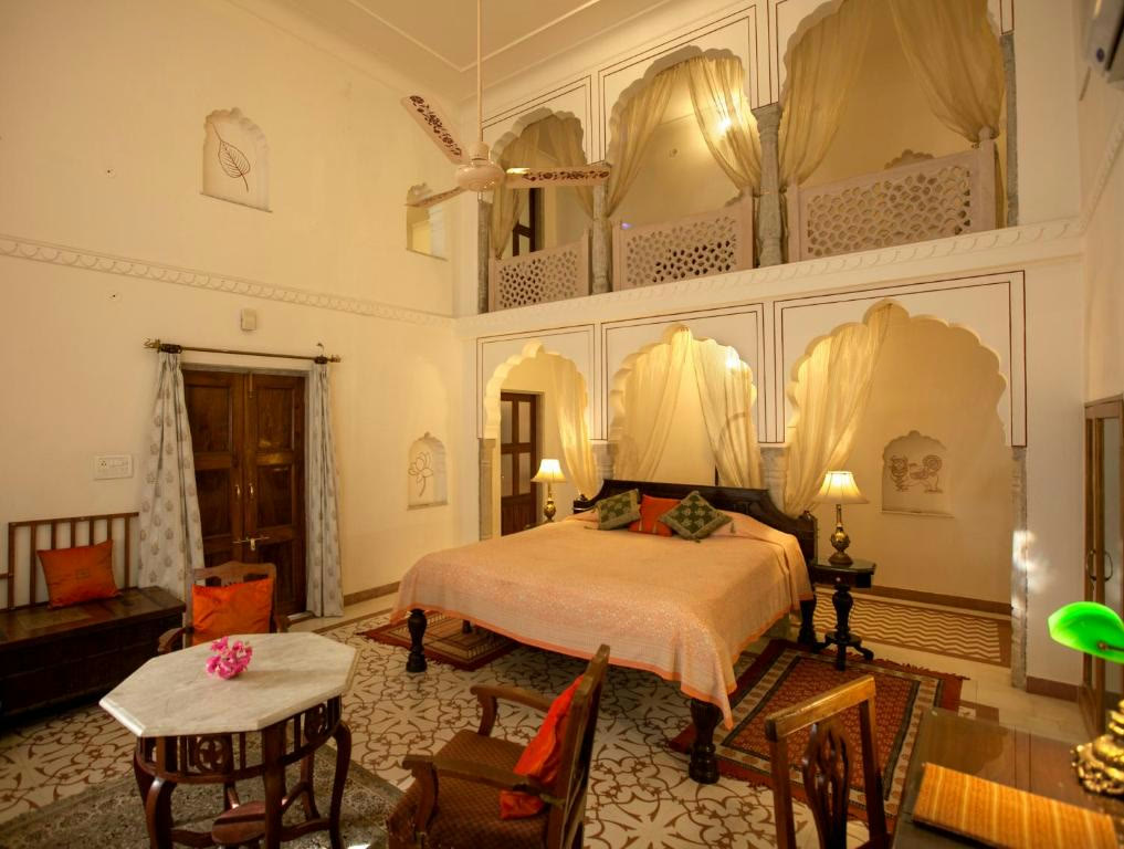Heritage room at Dera Mandawa, Jaipur, with carved arches and a gallery above the bed