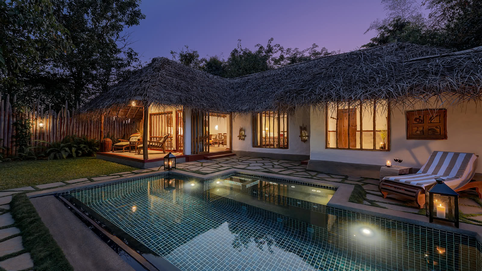 Thatched pool hut at Evolve Back Kuruba Safari Lodge, with its private pool lit at dusk
