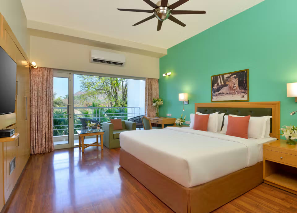 Room at Gir Serai, with a lion photograph above the bed and a balcony onto the trees