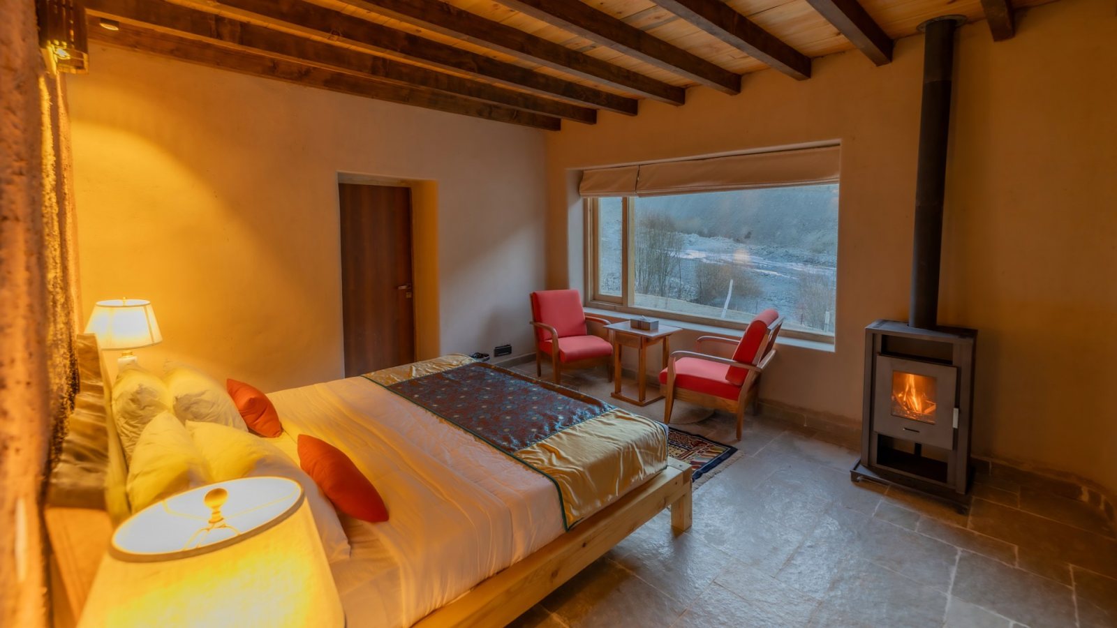 A bedroom at House of Rumbak, with a wood-burning stove and a window onto the mountains