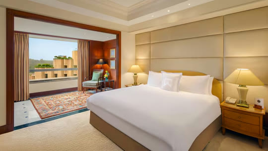 Guest room at ITC Maurya, with a wide bed and a balcony over New Delhi