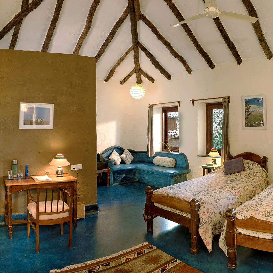 Room at The Sarai at Toria, with a timber-beamed roof, twin beds and a blue floor