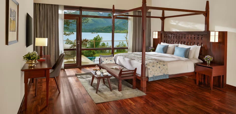 Room at Taj Wayanad, with a four-poster bed and a view over the lake