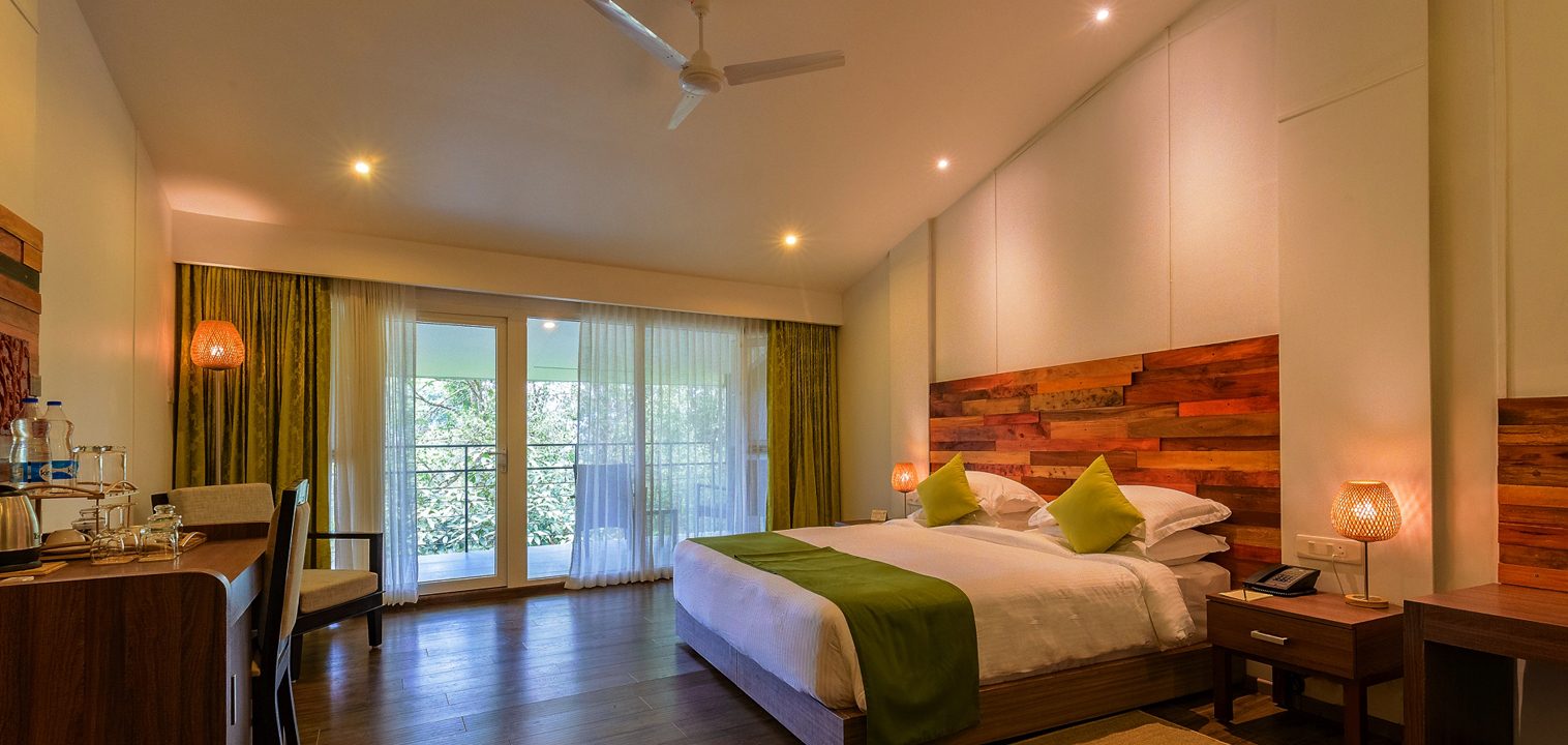 Bedroom with a timber headboard and wooden floors at Wayanad Wild, CGH Earth