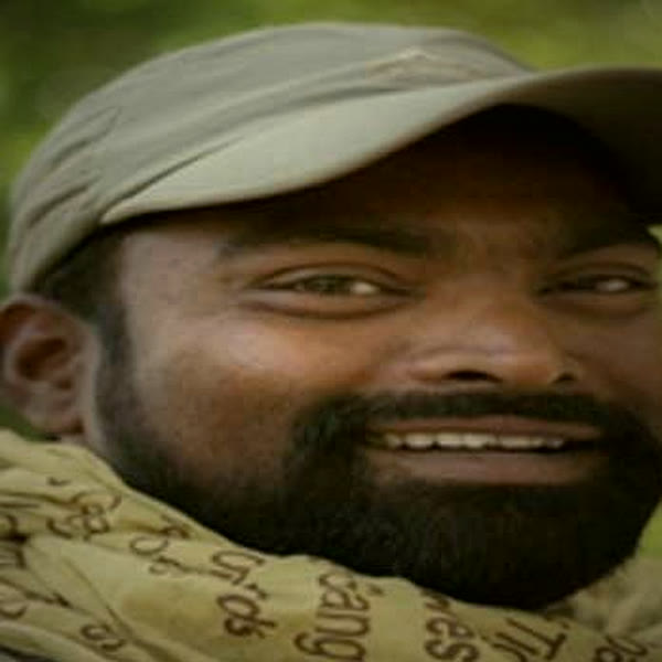Durgesh Kumar Singh in a cap and scarf in the forest